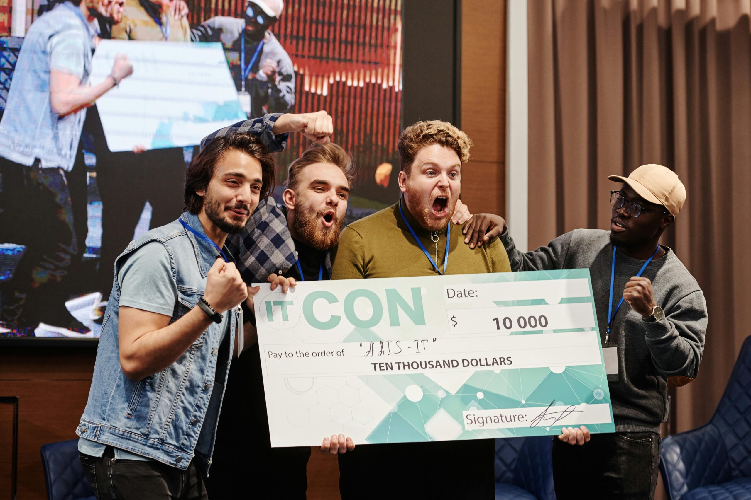 Excited group of men celebrate winning a $10,000 prize at an indoor IT conference.
